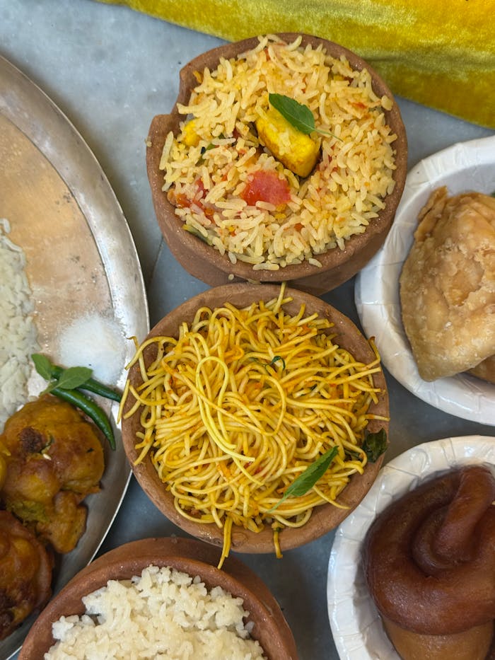 Traditional Indian cuisine featuring biryani, noodles, and samosas served in clay pots.