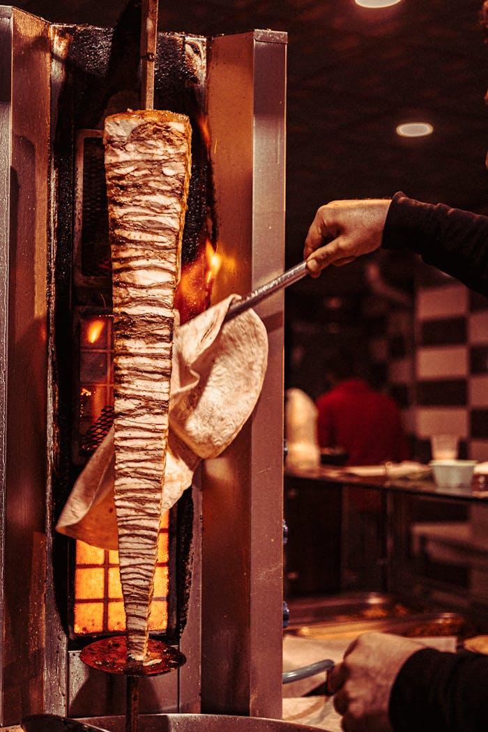 contact-img Close-up of shawarma being cooked on a rotisserie in a traditional Gaziantep restaurant.